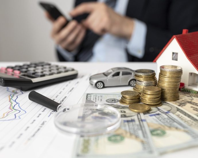 Financial assets including cash, coins, house model, and calculator illustrating RAG-powered loan analysis and improved contract processing efficiency.