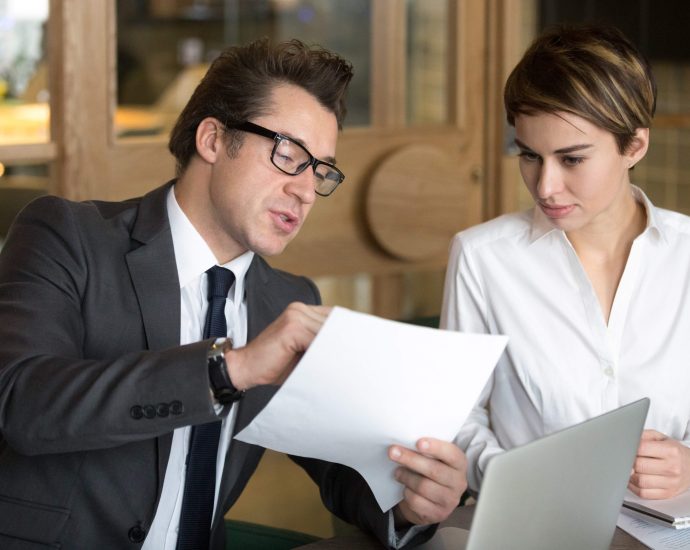 Business professionals reviewing contract documents together, representing accelerated loan processing through LLM orchestration and intelligent document analysis.