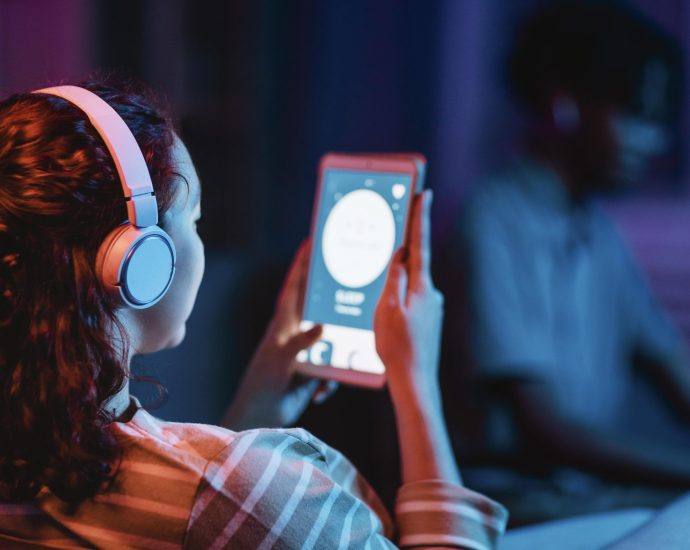 User listening to audio on a tablet with headphones, showcasing AI-powered content discovery and real-time predictive analytics reducing content overload.