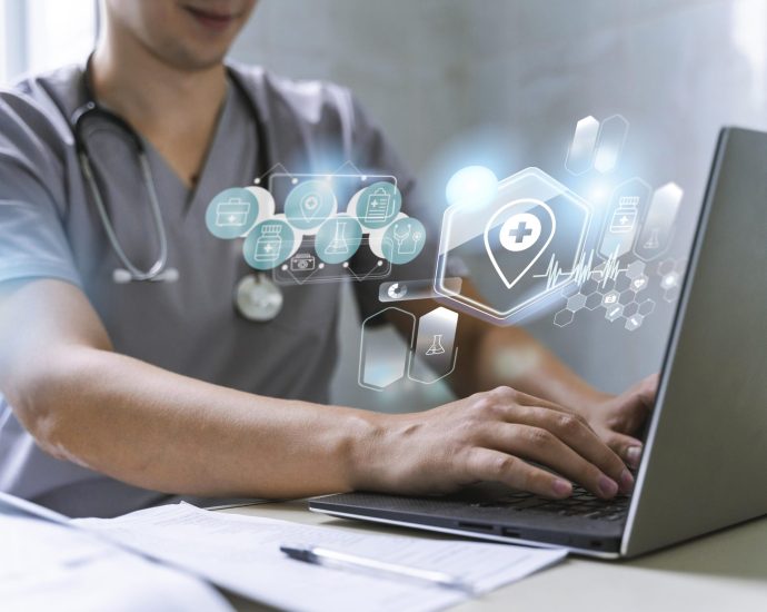 Healthcare professional using a laptop with digital health interface icons, representing secure HIPAA data management through predictive analytics and adaptive learning.