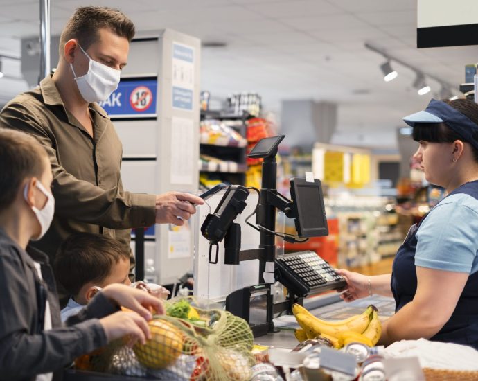 Retail checkout scene with cashier and customers purchasing groceries, showcasing computer vision and AI improving checkout speed and customer experience.