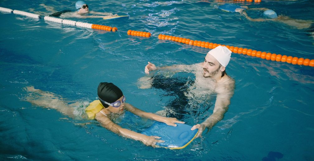 coach-teaching-kid-indoor-swimming-pool