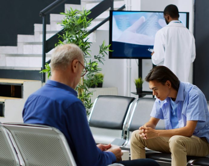 Patients waiting in a clinic reception area, highlighting scheduling inefficiencies solved by agentic AI and predictive analytics improving patient access.