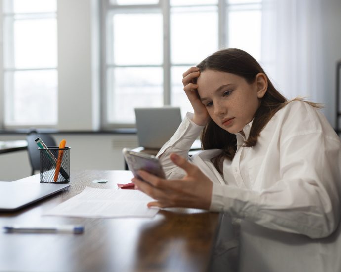 Teen user looking overwhelmed while using a smartphone, representing user friction fatigue caused by excessive digital interactions and poor mobile experiences.