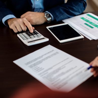 Financial professional reviewing loan documents and calculating credit data, illustrating automated credit processing and faster loan approval workflows using LLM orchestration.