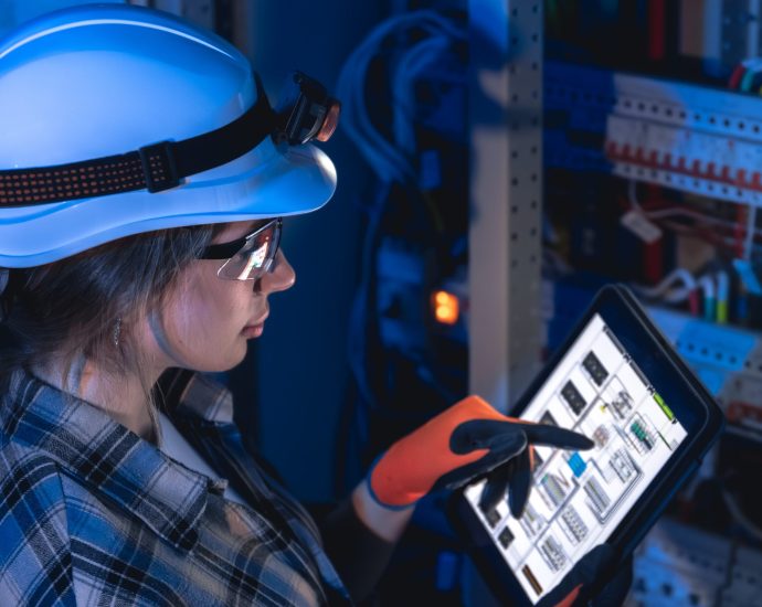 Technician using tablet to monitor electrical systems with real-time IoT data and predictive maintenance insights.