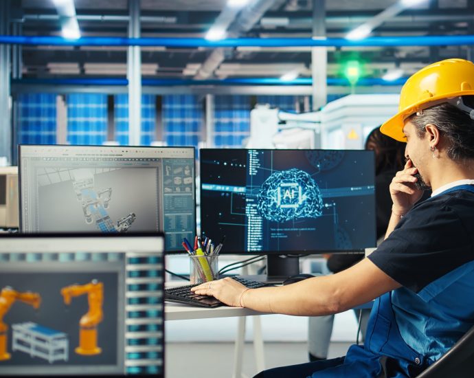 Engineer analyzing digital twin simulations and AI analytics to optimize robotic production and prevent downtime in a smart factory environment.